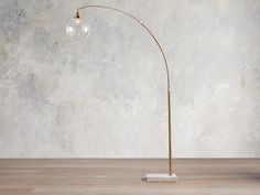 a lamp that is on top of a wooden floor in front of a concrete wall