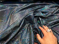 a person's hand on top of a shiny cloth with an intricate design in the middle