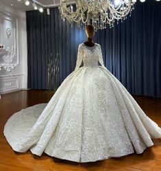 a white wedding dress on display in a room with chandelier and blue curtains