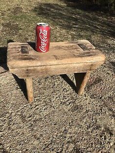 an old wooden bench with a can of coca - cola sitting on top of it