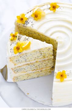 there is a cake with white frosting and yellow flowers on the top it has one slice cut out