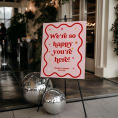 a sign that says we're so happy you're here with two shiny balls