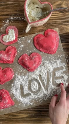 someone is making heart shaped cookies on a table