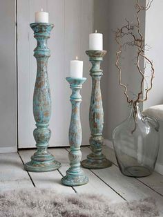 three tall candlesticks sitting on top of a wooden floor