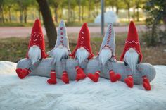 four red and white gnomes sitting on top of a blanket