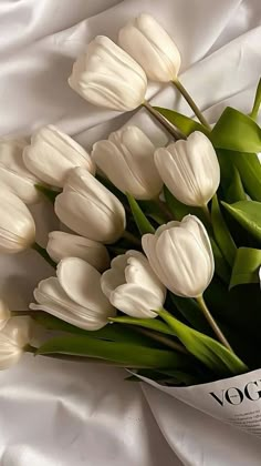 a bouquet of white tulips laying on top of a bed