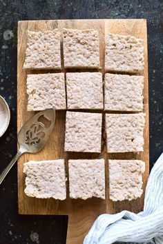 several squares of rice krispy treats on a cutting board next to a measuring spoon