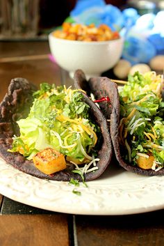 two tortillas filled with lettuce and other vegetables on a white plate