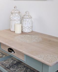 a wooden table with two white vases sitting on it's sides and a candle in the middle