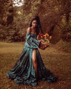 a woman in a blue dress is holding a basket with flowers on it and posing for the camera