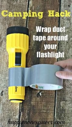 a hand holding a tape around a flashlight on top of a wooden table with text reading camping hack wrap duct tape around your flashlight