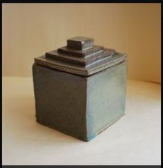 a ceramic container sitting on top of a white table next to a wall in the background