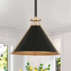 a black and gold pendant light hanging over a dining room table with yellow flowers on it