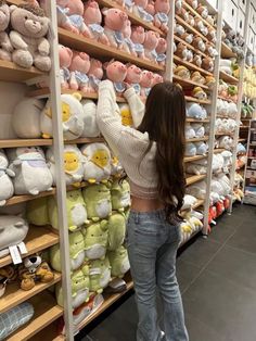 a woman is looking at stuffed animals on display in a store with shelves full of teddy bears