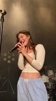 a woman singing into a microphone while standing in front of a microphone on a stage