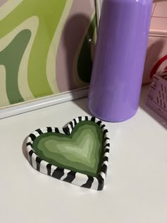 a heart shaped paper plate sitting on top of a table next to a purple vase