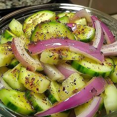 sliced cucumbers and onions in a bowl with seasoning on top, ready to be cooked