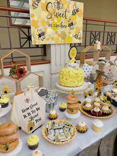 a table topped with cakes and cupcakes covered in frosting next to a sign that says sweet as can bee