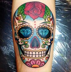 a colorful skull tattoo with a rose on it