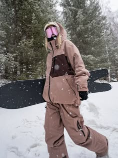 a snowboarder is walking through the snow with his board in hand and wearing goggles