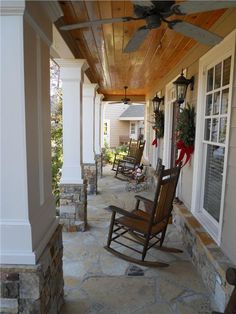 a porch with rocking chairs on it and a ceiling fan hanging from the ceiling above