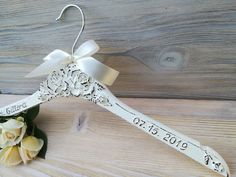 a wedding dress hanger with a flower and ribbon attached to it on a wooden surface