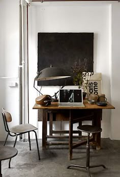 a desk with a laptop computer on it in front of a blackboard and chair