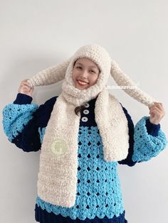 a woman wearing a blue and white crocheted coat with a hood over her head