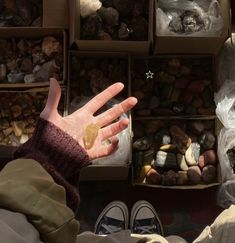 a person with their hand out in front of many boxes full of rocks and stones