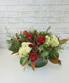 a green vase filled with red and white flowers