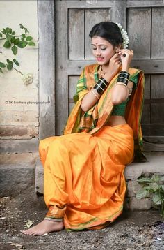 a woman in an orange and green sari sitting on the steps talking on her cell phone