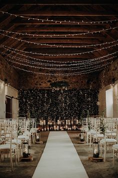 an indoor wedding venue with white chairs and string lights