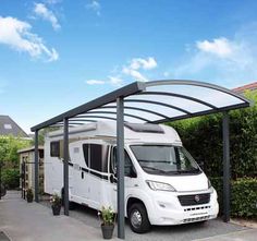 a white motorhome parked in front of a house with an awning over it