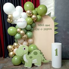 a green dinosaur balloon arch with balloons