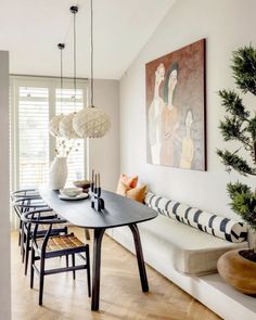 a dining room table and chairs in front of a painting on the wall next to a bench