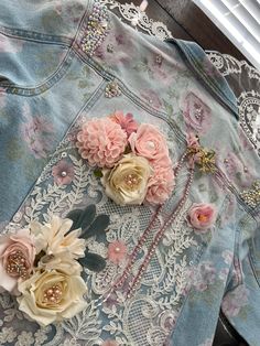 three flowers are placed on the back of a jean jacket, which is adorned with lace