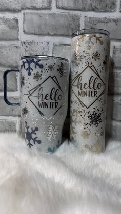 two coffee mugs sitting next to each other on top of a white fur rug