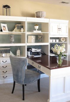 a desk with a chair and some bookshelves on it in front of a window