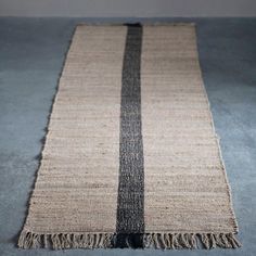 a black and white striped rug with fringes on the bottom, sitting on a gray floor