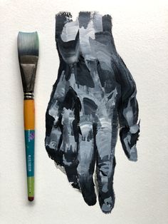 a paintbrush next to a hand painted with black and white