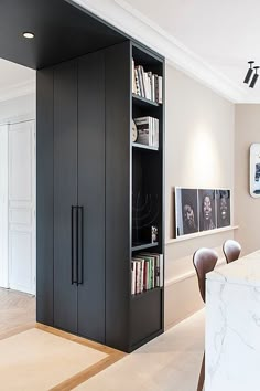 an open bookcase in the corner of a room with chairs and a marble counter top