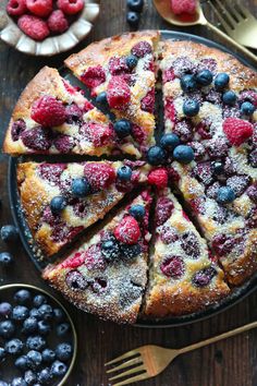 a cake with blueberries and raspberries on it is cut into eight slices