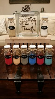 there is a table with some jars on it and a sign above the jars that says together we make a family