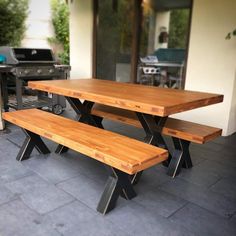 two wooden benches sitting on top of a patio next to an outdoor bbq grill