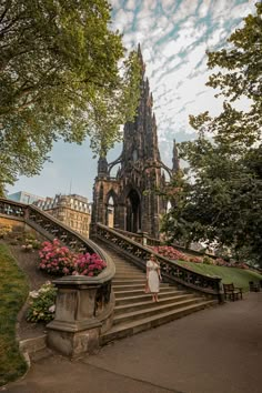 a woman is walking down some stairs in front of a castle