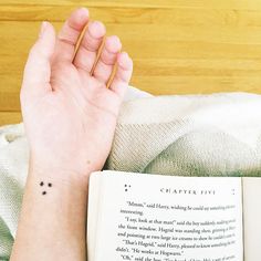 a woman's hand with a tiny star tattoo on her wrist next to an open book