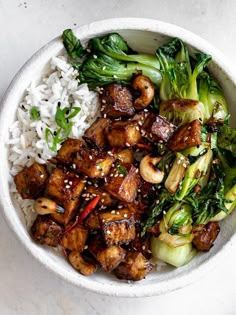 a white bowl filled with rice and meat next to broccoli on top of a table