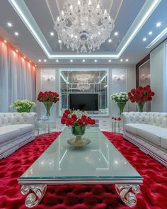 a living room filled with white couches and red carpeted flooring topped by a chandelier