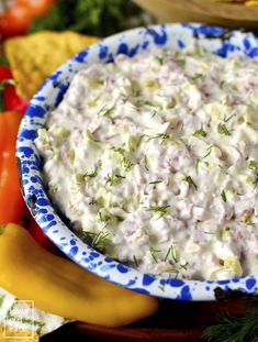 a blue and white bowl filled with food on top of a table next to vegetables