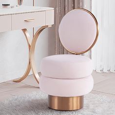 a pink chair sitting on top of a white rug next to a desk with a mirror